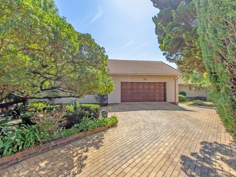 Front view of the property featuring a paved driveway, double garage, and well-maintained landscaped garden.