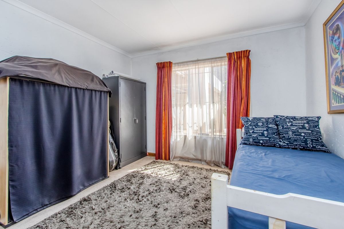A standard bedroom featuring neutral walls, coving, and a window with curtains, providing a functional space for rest.