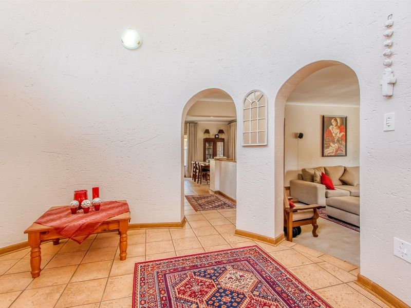 An inviting entryway featuring distinctive arched doorways leading into the living and dining areas, finished with neutral textured walls and tiled flooring.