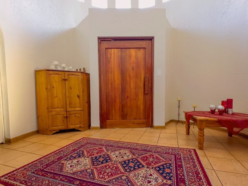 Spacious entrance hall featuring ceramic tile flooring, a solid wood front door, and high-level clerestory windows providing natural light.