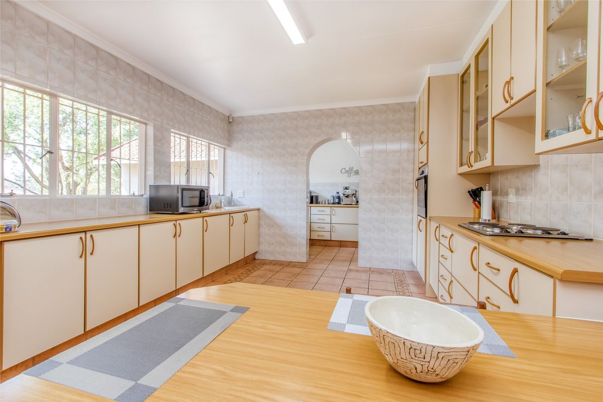 A functional kitchen featuring ample built-in cabinetry, laminate countertops, a built-in oven, and a hob, with a convenient adjoining scullery area.