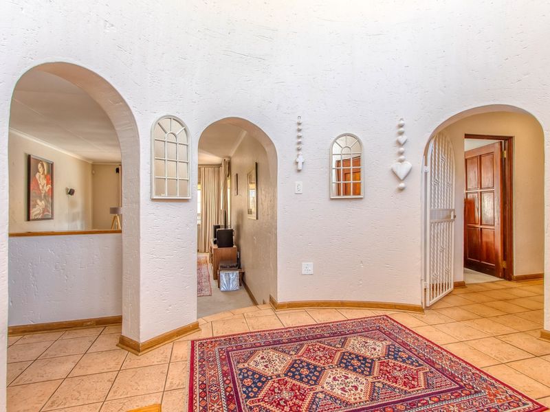 A central hallway featuring distinctive arched doorways, tiled flooring, and textured walls, providing access to multiple rooms within the home.