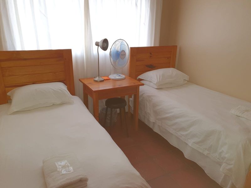 A functional bedroom featuring tiled flooring and natural light through window curtains, suitable for a guest room or children's bedroom.