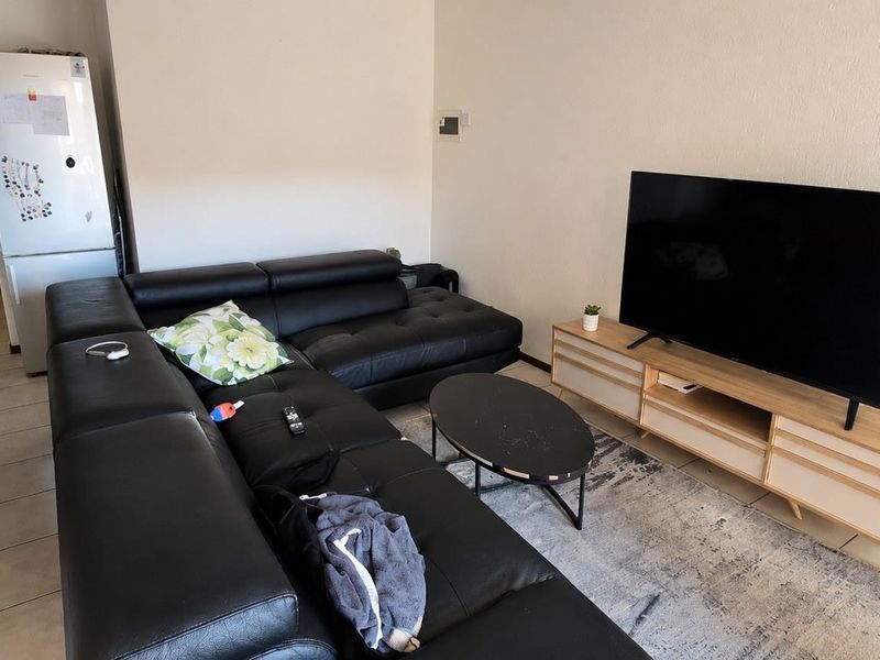 A functional living room area featuring tiled flooring and a neutral wall finish, providing a comfortable space for relaxation.
