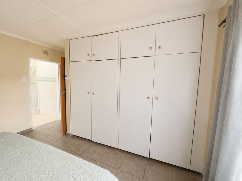 A bedroom featuring built-in cupboards, tiled flooring, and direct access to an en-suite bathroom.
