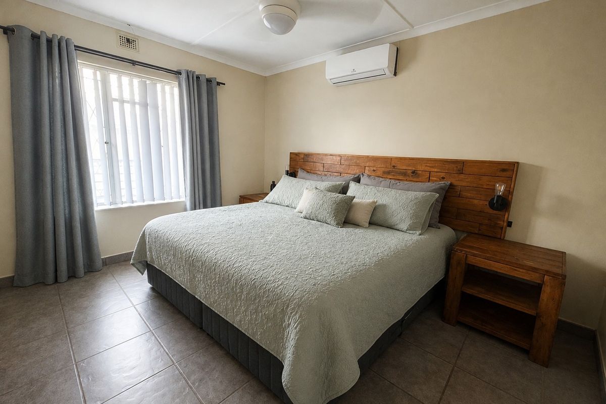 A well-maintained bedroom featuring tiled flooring, a ceiling fan, and a wall-mounted split-system air conditioner.