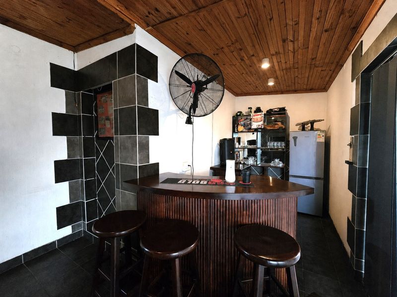 A dedicated bar area featuring a built-in counter, timber ceiling, and decorative tiled wall accents, providing a functional space for entertainment.