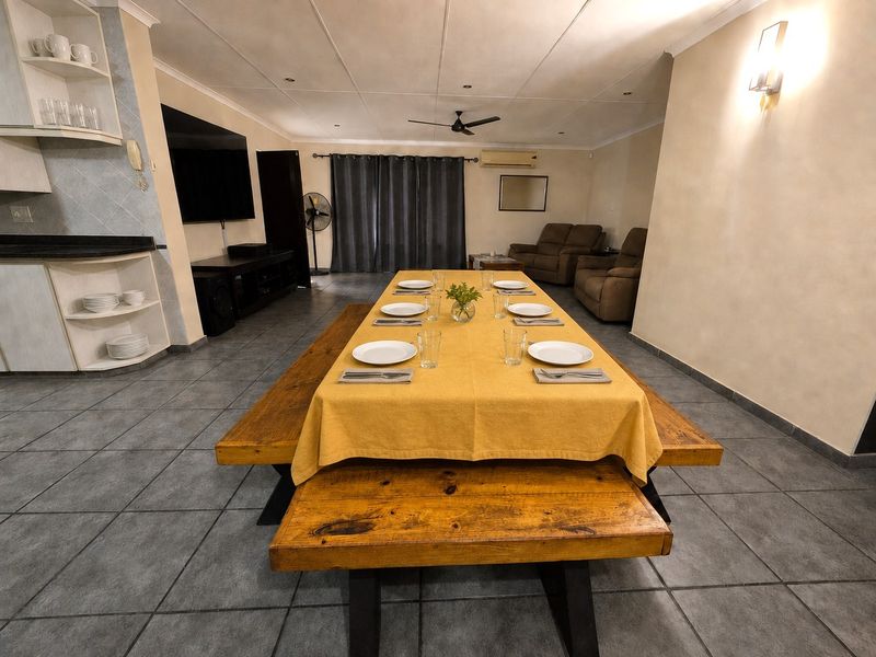 Spacious open-plan living and dining area featuring tiled flooring, recessed lighting, and a wall-mounted air conditioning unit.