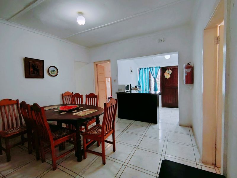 Open plan dining area featuring tiled flooring and a kitchen island, providing a functional layout with direct access to the kitchen and adjacent rooms.
