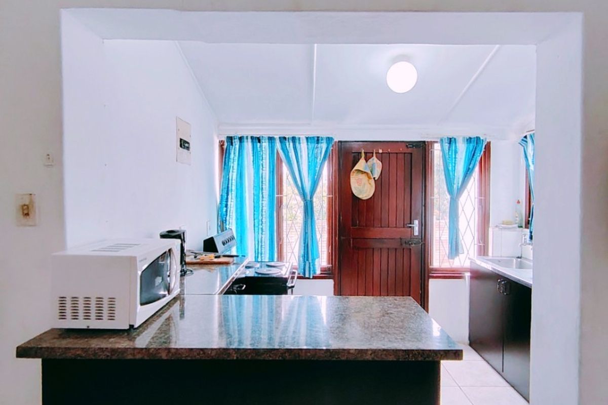 A functional kitchen featuring granite countertops, built-in cabinetry, and a hob, with direct access to an exterior door.