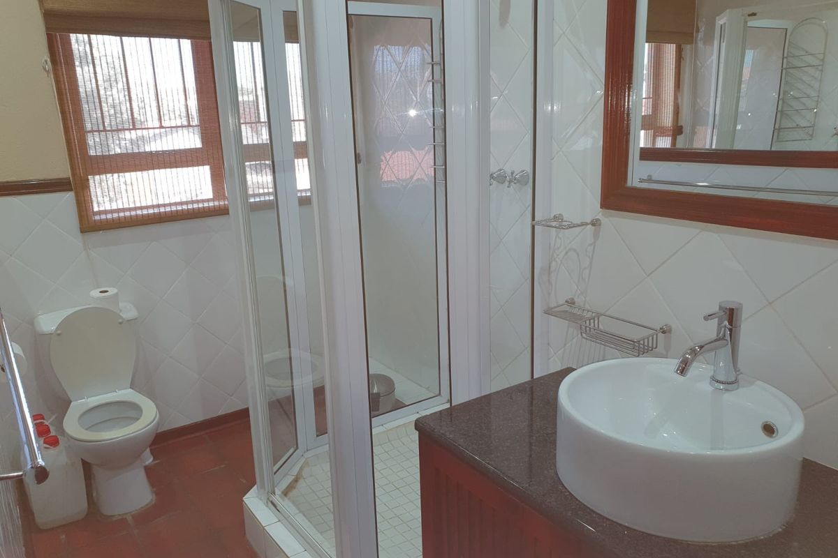 A functional bathroom featuring a shower enclosure, a vessel sink set on a granite vanity, and tiled finishes throughout.