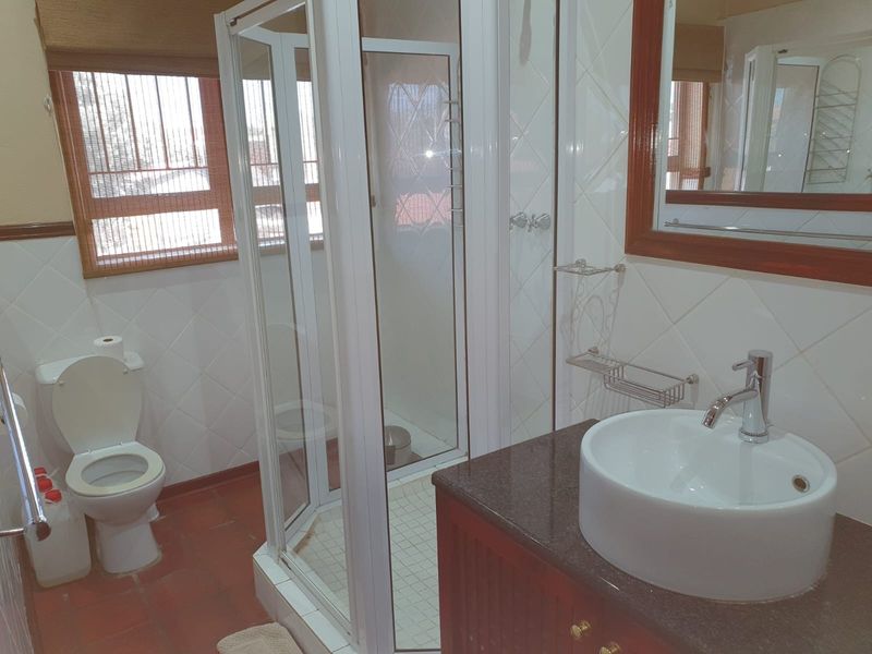 A functional bathroom featuring a shower enclosure, a vessel sink set on a granite vanity, and tiled finishes throughout.