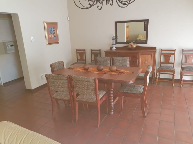 A traditional dining room featuring terracotta floor tiles and neutral wall finishes, providing a functional space for family meals.
