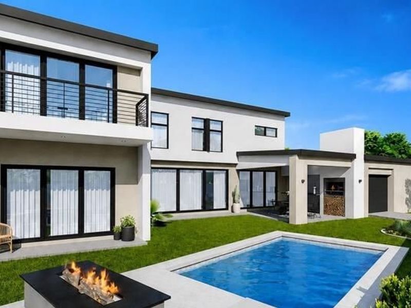 Modern double-storey rear elevation featuring a swimming pool, paved patio area, built-in braai, and a balcony overlooking the landscaped garden.