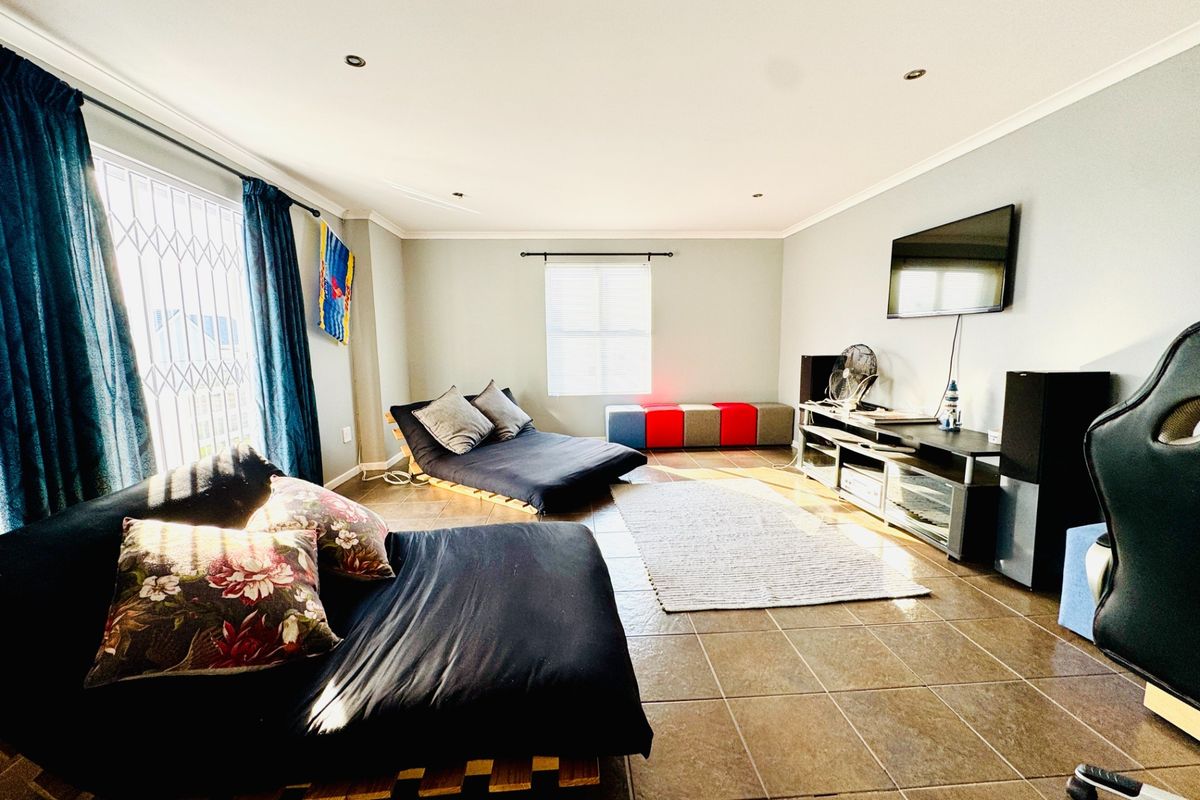 Spacious living room featuring tiled flooring, recessed downlighting, and a security gate on the window, offering a functional and well-lit living space.