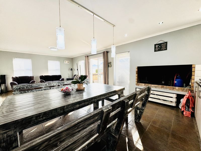 Spacious open-plan living and dining area featuring tiled floors, a built-in fireplace, and direct access to the outdoor patio through sliding glass doors.
