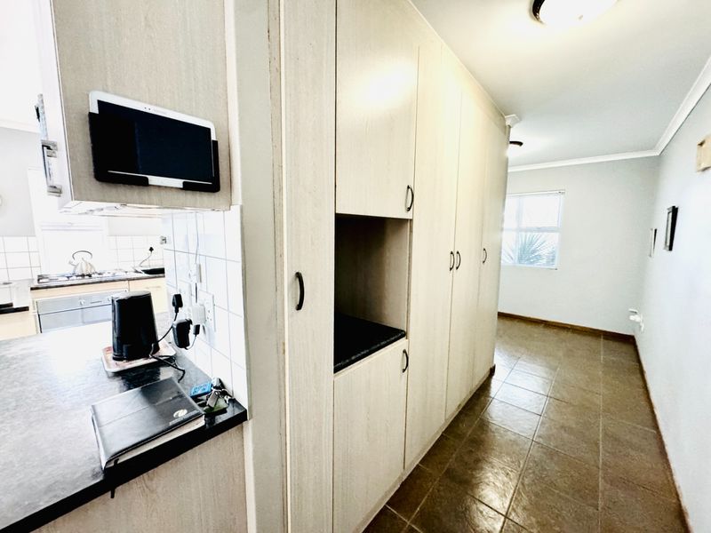 A functional kitchen area featuring extensive built-in cabinetry, laminate countertops, and tiled flooring, providing ample storage and workspace.