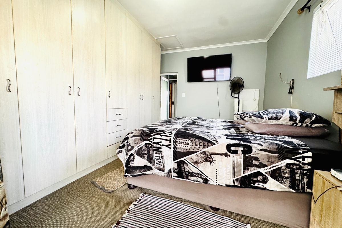 A bedroom featuring extensive built-in cupboards, carpeted flooring, and a window with venetian blinds.
