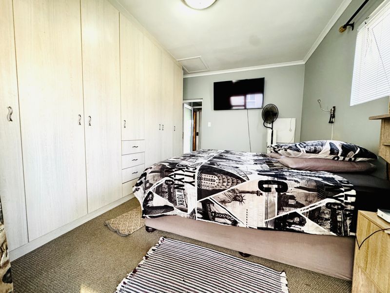 A bedroom featuring extensive built-in cupboards, carpeted flooring, and a window with venetian blinds.