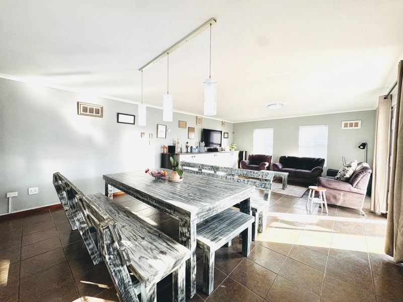 Spacious open-plan living and dining area featuring tiled flooring, neutral wall tones, and integrated lighting fixtures.