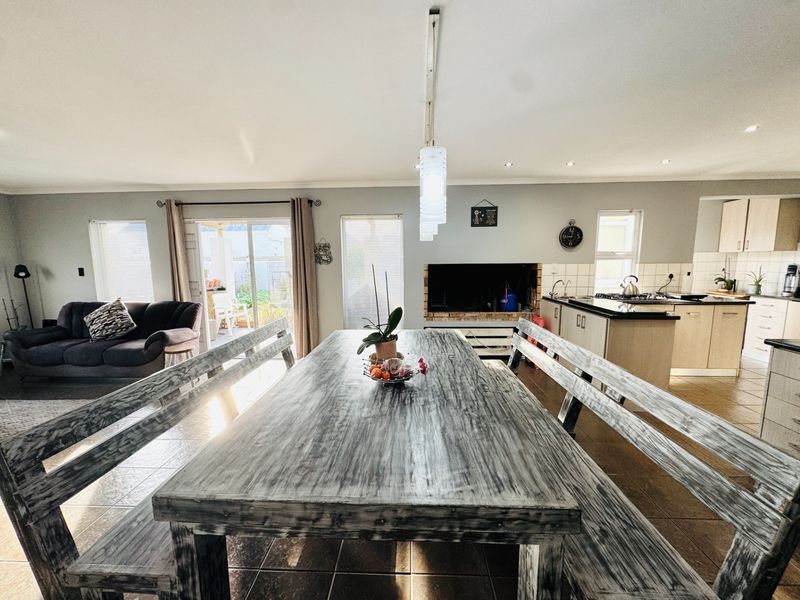 Spacious open-plan living and dining area featuring a functional kitchen with built-in appliances, tiled floors, and direct access to the outdoor patio.