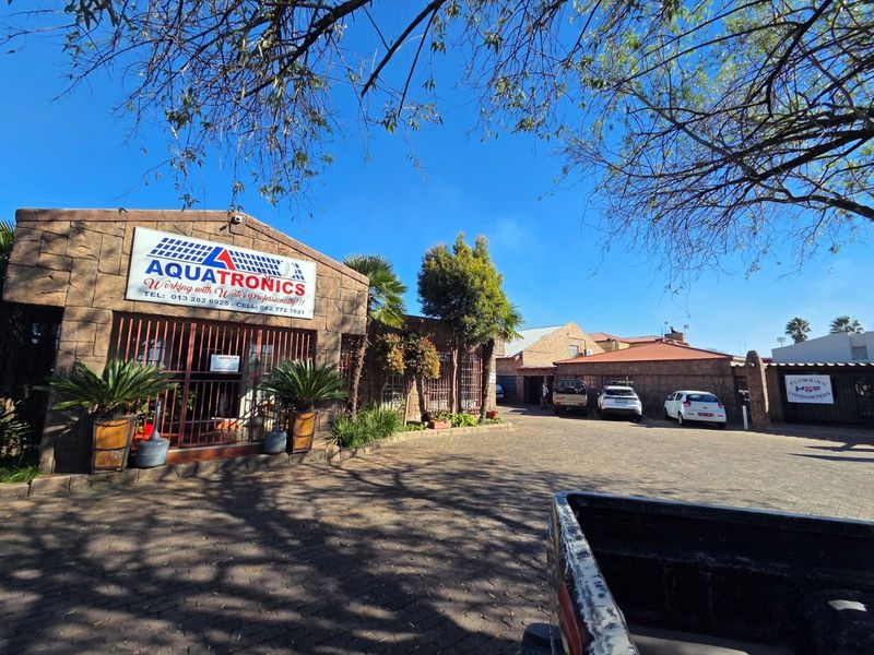Front exterior view of a commercial property featuring stone cladding, paved driveway, and secure gated access.
