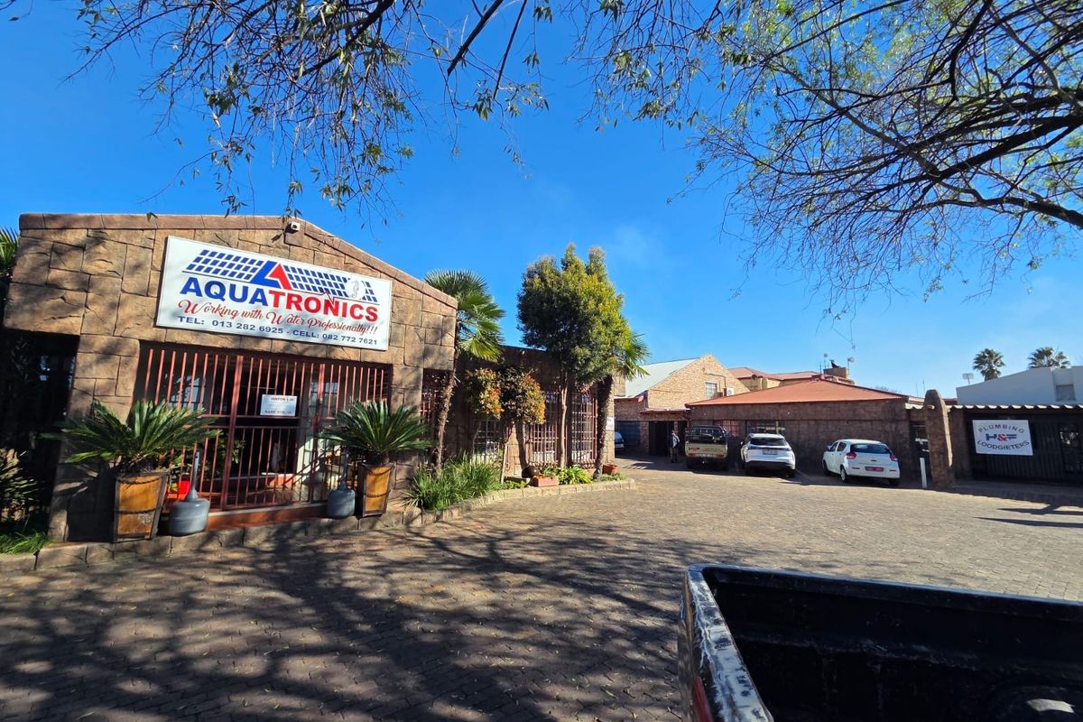 Front exterior view of a commercial property featuring stone cladding, paved driveway, and secure gated access.