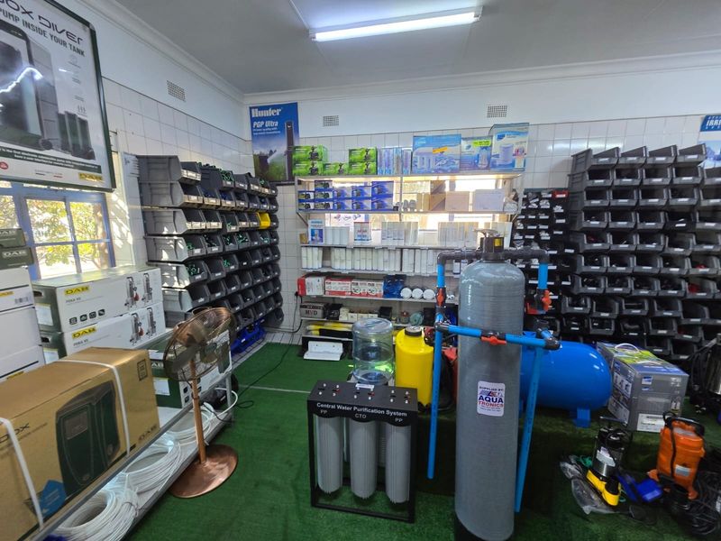 A commercial utility or storage space featuring tiled walls, extensive shelving for inventory, and a central water purification system.