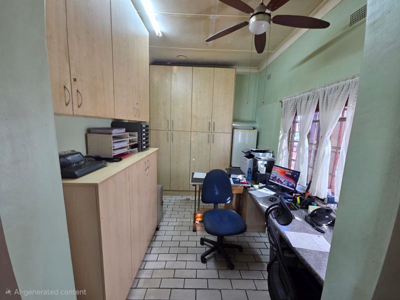 A functional office space featuring extensive built-in cabinetry, a fixed desk area, tiled flooring, and a ceiling fan.
