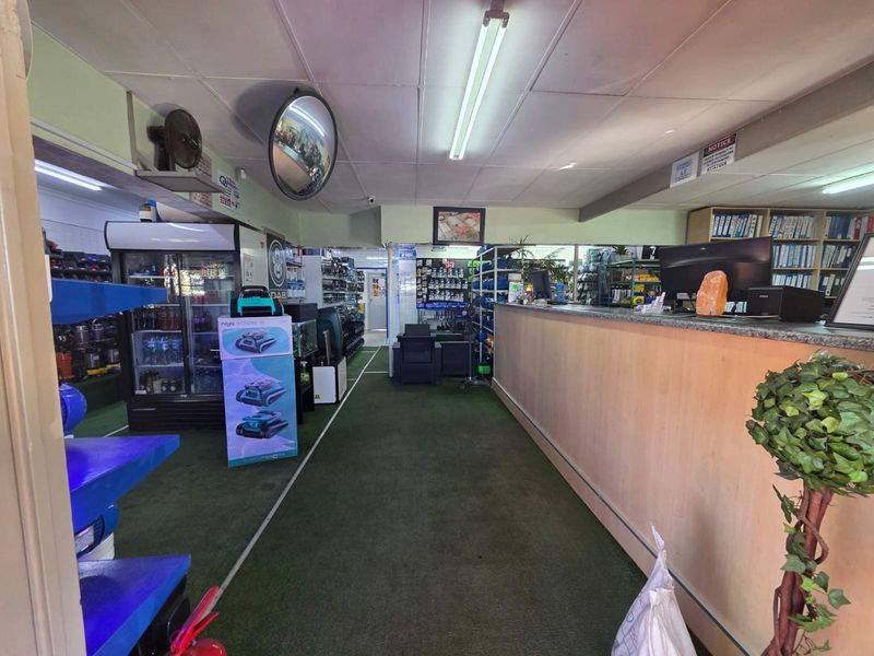 Commercial retail space featuring a long service counter, suspended ceiling, and fluorescent lighting, currently utilized for product display and customer service.