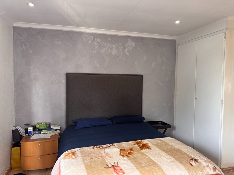 A bedroom featuring built-in cupboards, recessed downlighting, and a textured feature wall.