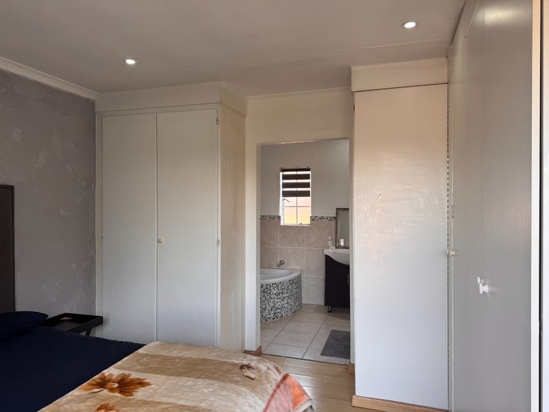 Bedroom featuring built-in cupboards and direct access to an en-suite bathroom with a corner bathtub.