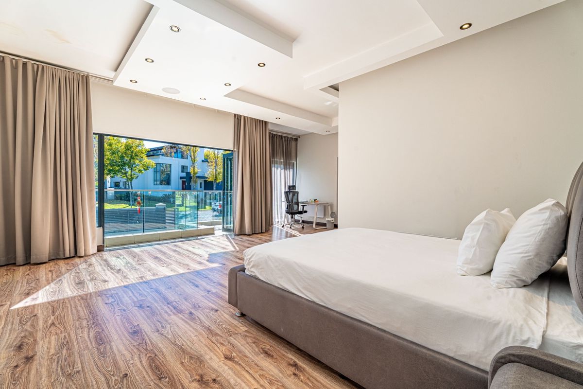 Spacious bedroom featuring laminate flooring, recessed ceiling lighting, and large sliding glass doors opening to a balcony with neighborhood views.