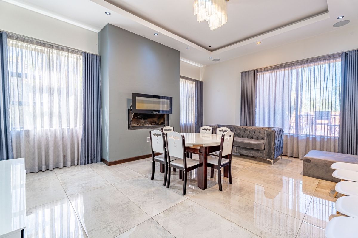 Spacious living area featuring large format tiled flooring, a built-in fireplace, and a decorative tray ceiling with recessed lighting.