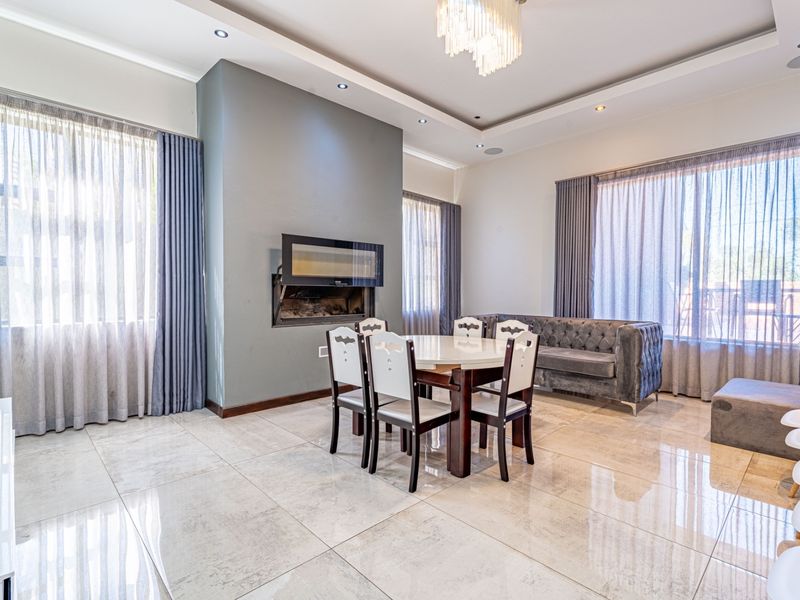 Spacious living area featuring large format tiled flooring, a built-in fireplace, and a decorative tray ceiling with recessed lighting.