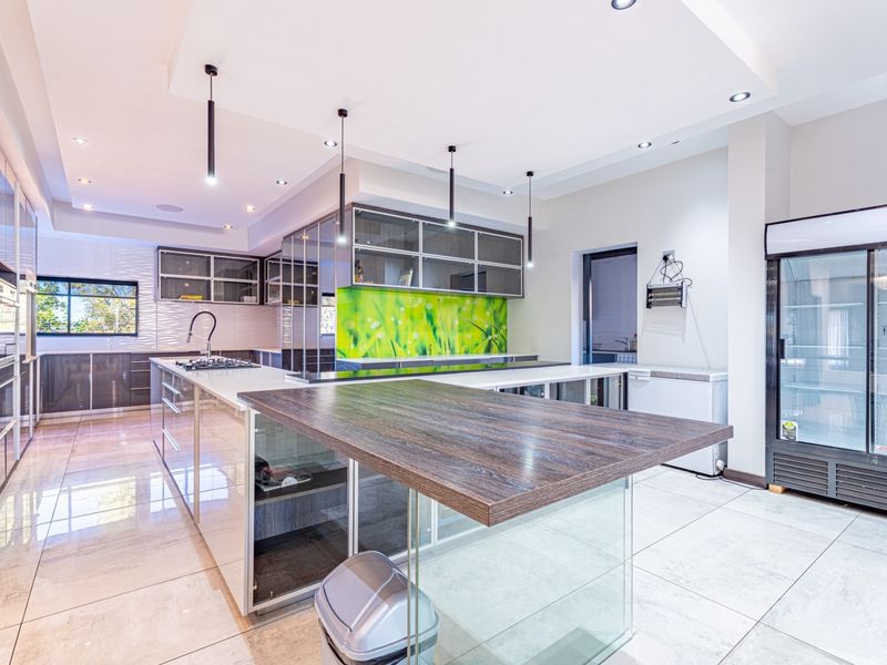 Modern kitchen featuring a large island, sleek built-in cabinetry, gas hob, and contemporary tiled flooring with recessed lighting throughout.