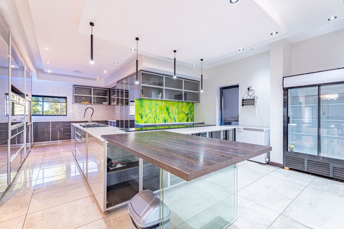 Modern kitchen featuring a large island, sleek built-in cabinetry, gas hob, and contemporary tiled flooring with recessed lighting throughout.