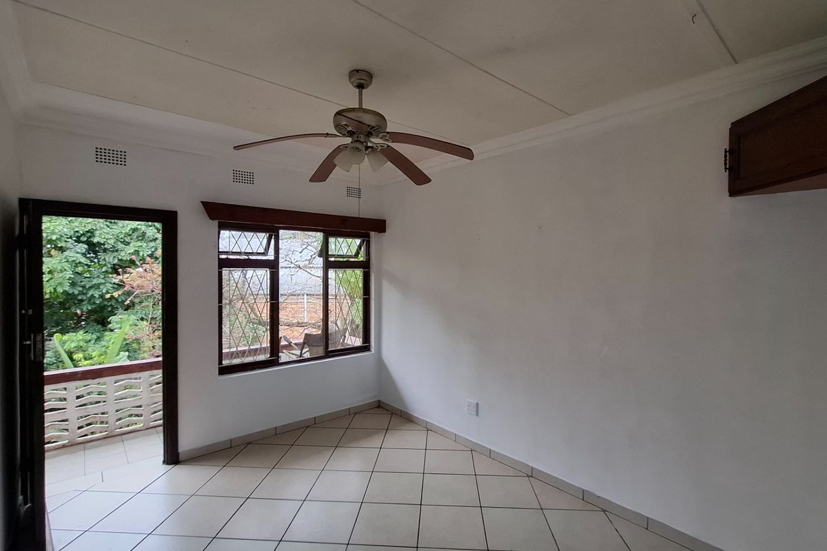 An empty living room featuring tiled floors, a ceiling fan, and direct access to an outdoor balcony area.