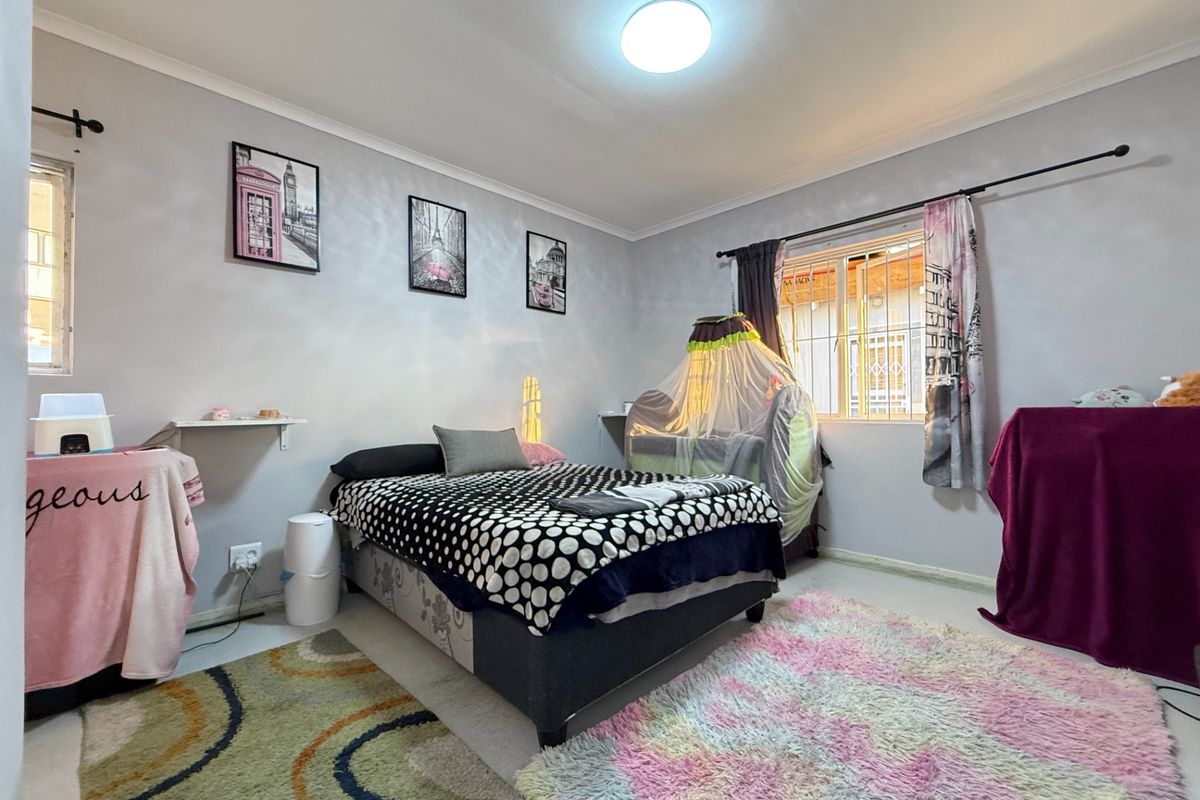 A functional bedroom featuring security bars on the windows, neutral wall finishes, and standard electrical fixtures, providing a comfortable and practical living space.