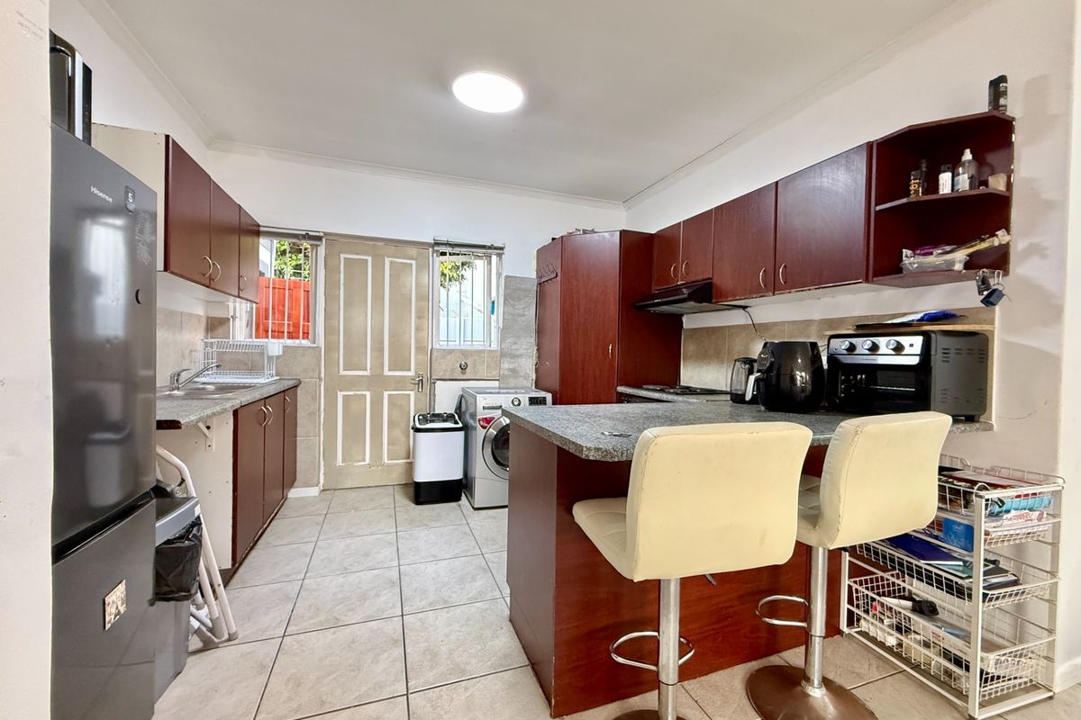 Functional kitchen featuring dark wood cabinetry, granite countertops, tiled flooring, and an integrated breakfast nook area with direct exterior access.