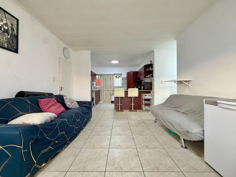 Open plan living and kitchen area featuring tiled flooring and a breakfast bar, providing a functional layout for daily living.