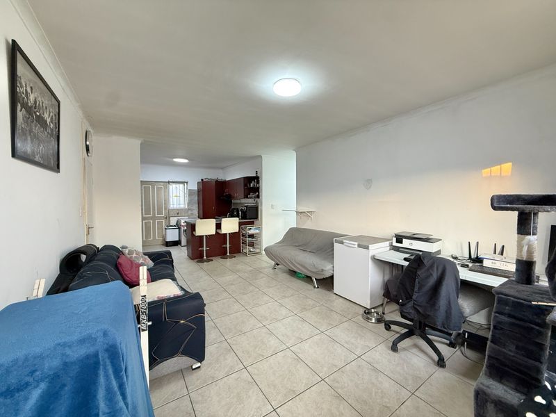 Open plan living area featuring tiled flooring and a connected kitchen space with built-in cabinetry and a breakfast bar.