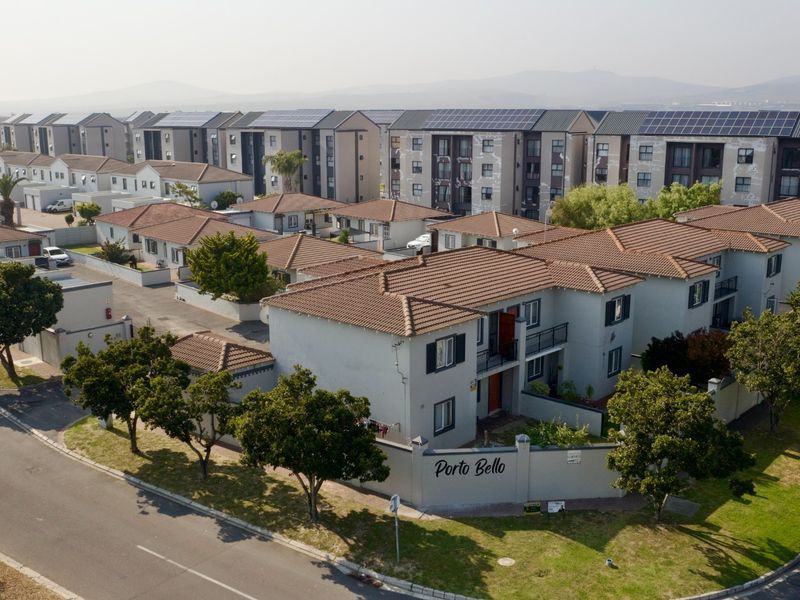 Aerial view of the Porto Bello residential complex featuring multiple housing units with tiled roofs, paved driveways, and solar panel installations.