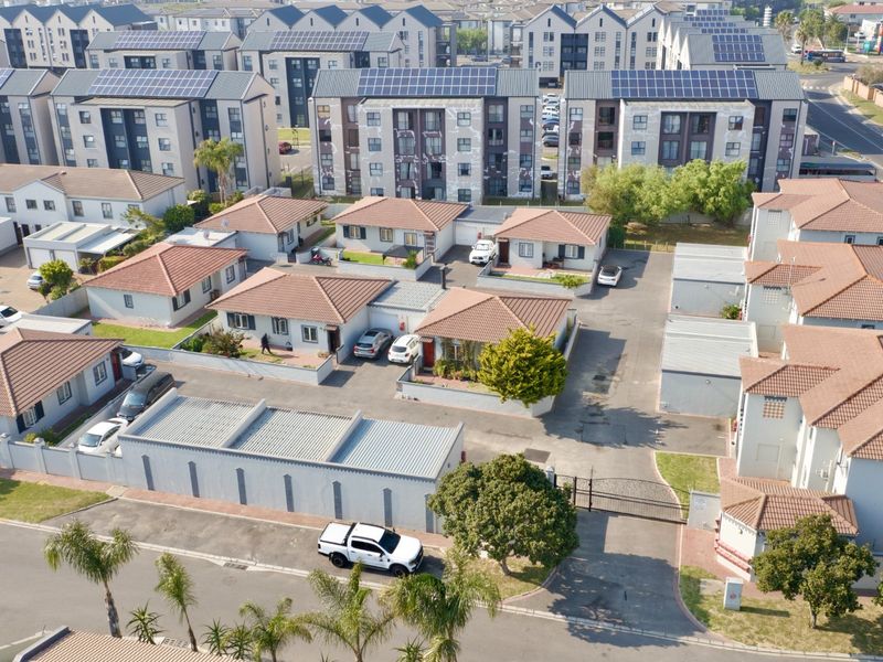 Aerial view of a residential complex featuring multiple detached houses with tiled roofs, paved driveways, and secure perimeter fencing.