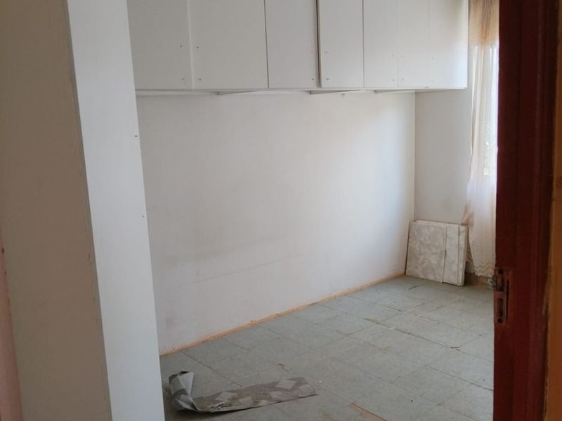 An empty bedroom featuring built-in overhead cabinetry, requiring significant renovation to the ceiling and flooring finishes.
