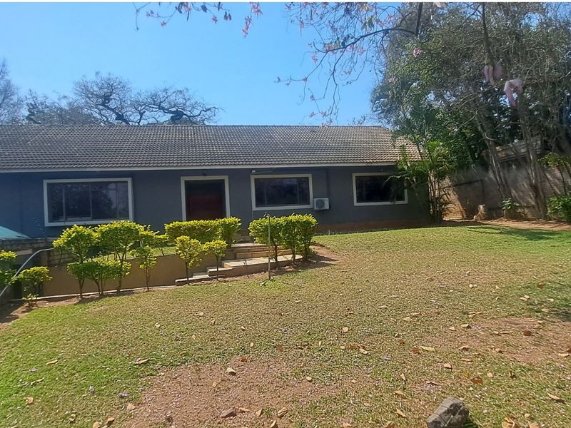 Rear view of a single-story house featuring a tiled roof, established garden, and paved access steps.
