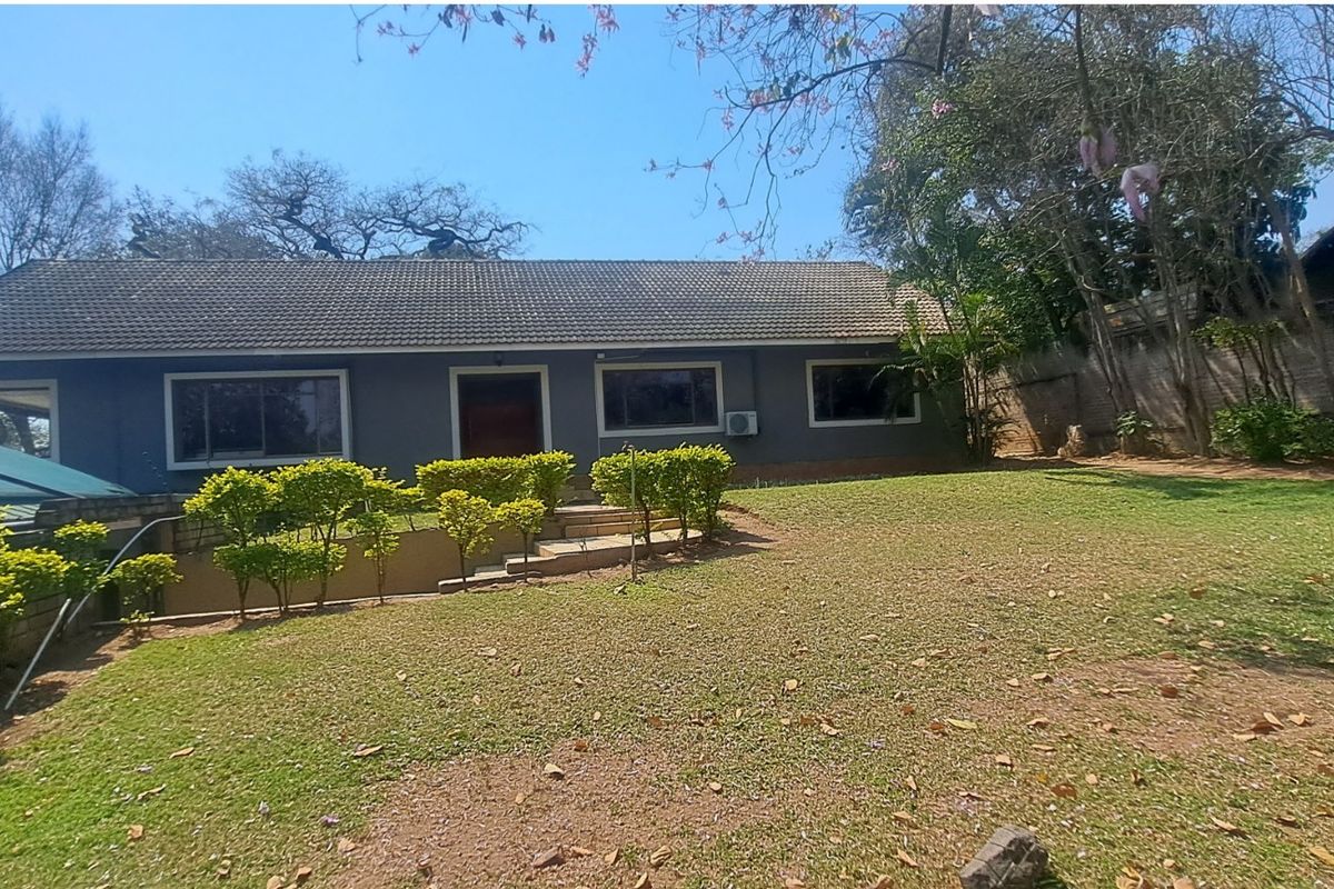 Rear view of a single-story house featuring a tiled roof, established garden, and paved access steps.