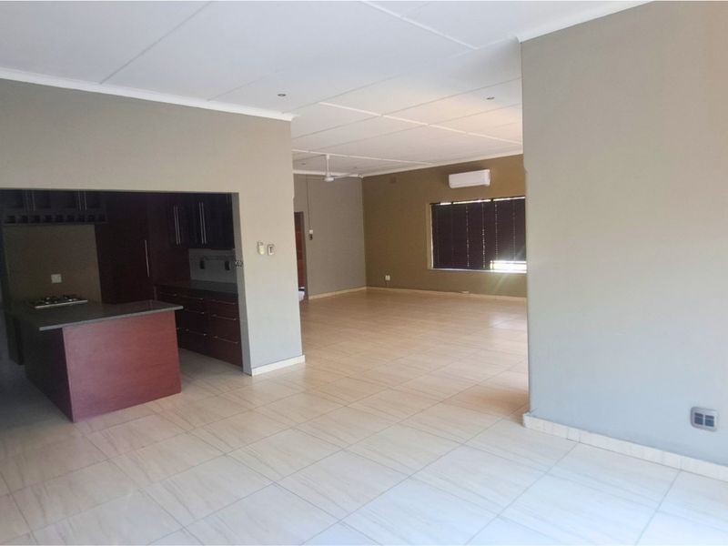 Spacious open-plan living area featuring tiled flooring, recessed lighting, and an integrated kitchen with cabinetry and a central island.