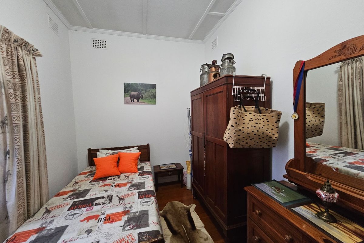 A bedroom featuring timber flooring and traditional ceiling cornicing, offering a functional space with neutral wall finishes.