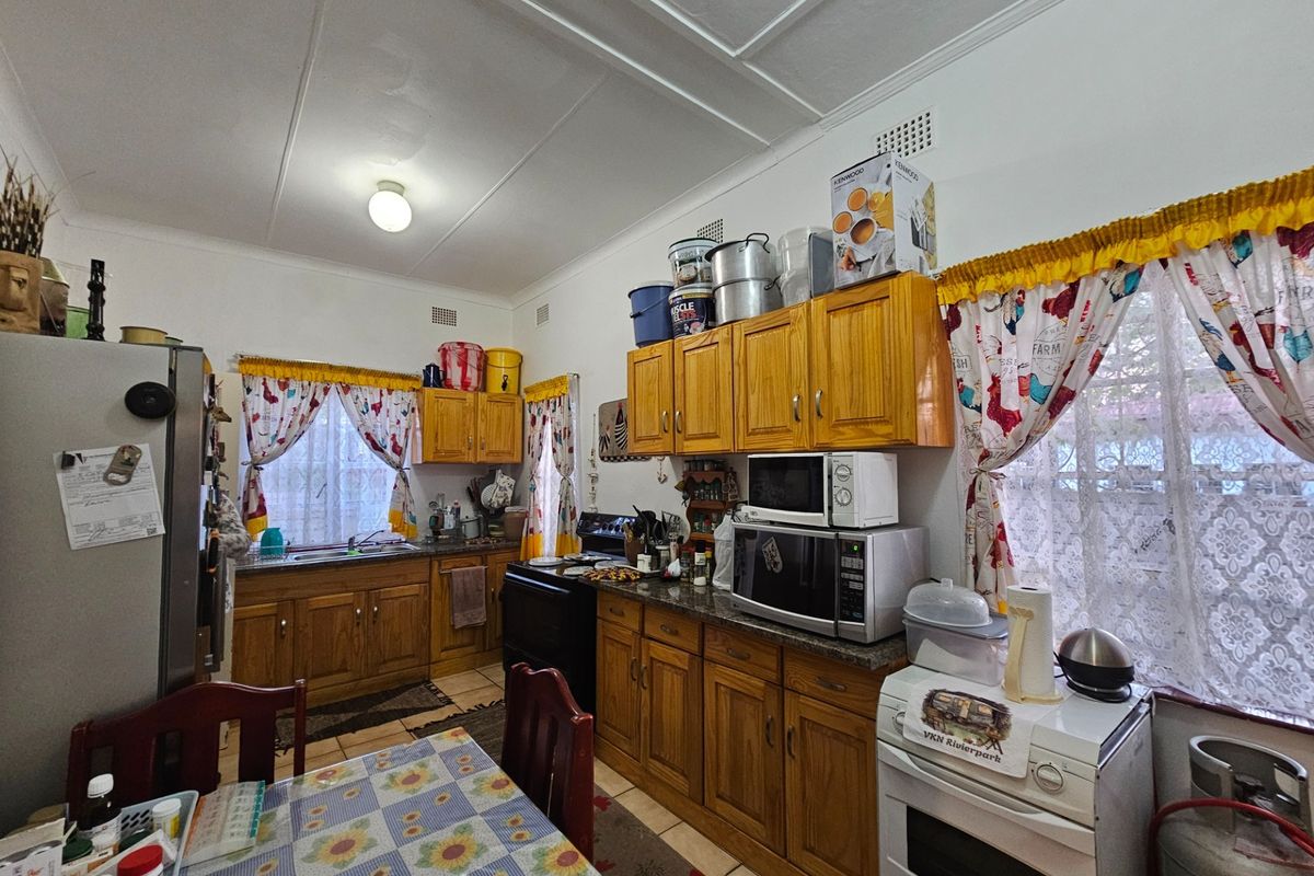 A functional kitchen featuring traditional wooden cabinetry, laminate countertops, and a freestanding stove, offering a classic layout with ample storage space.